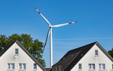 Image of wind turbine located in behind two houses 